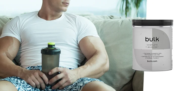 Muscular person holding Bulk Powders T-Booster supplement drink