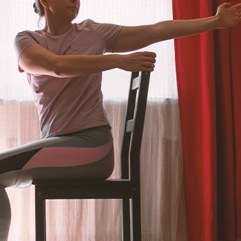 A senior doing chair yoga at home