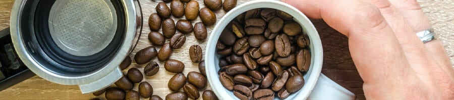close up image of a person holding a cup of coffee beans
