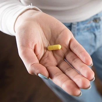 A close up shot of a woman holding a nootropic supplement on her palm