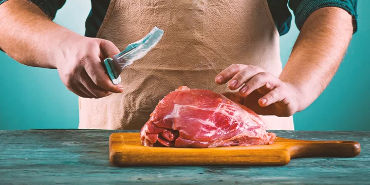 A butcher slicing up meat on a chopping board