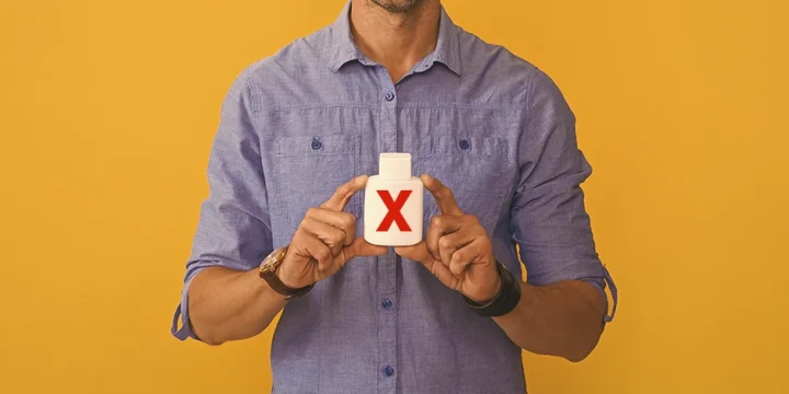 A person holding nootropic pills with a big red X on it