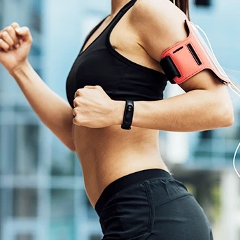A woman running outdoors while wearing a fitness tracker watch