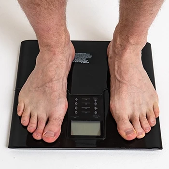 A close up shot of a man on a weight scale